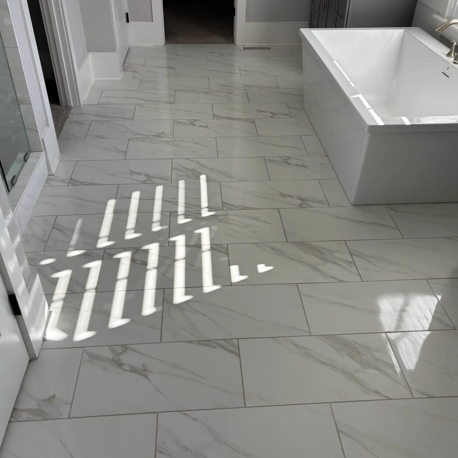 Freshly cleaned marble-look tile floor and grout in a sunlit bathroom